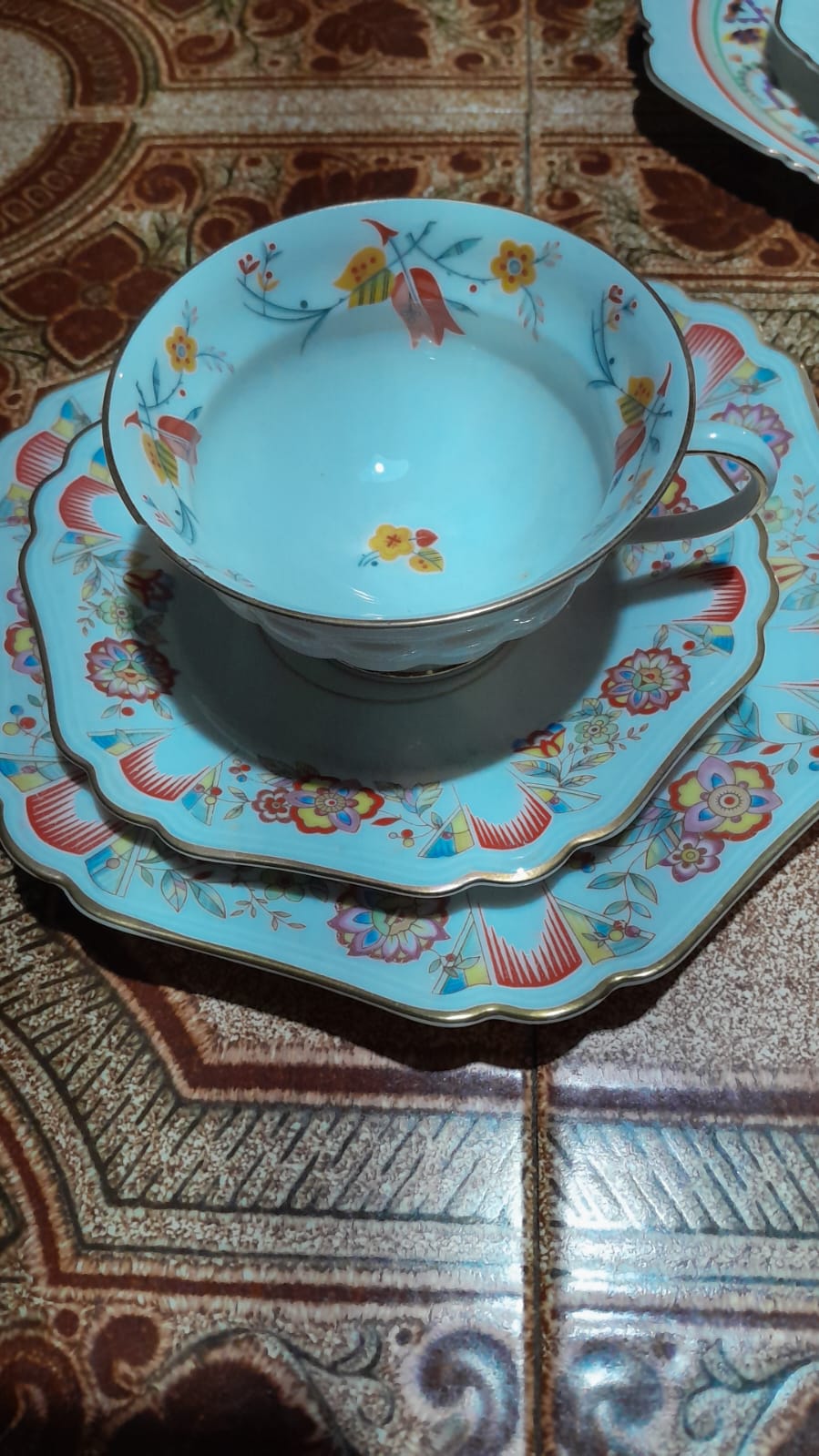 Xícara e pires em porcelana azul-clara com flores e detalhes dourados